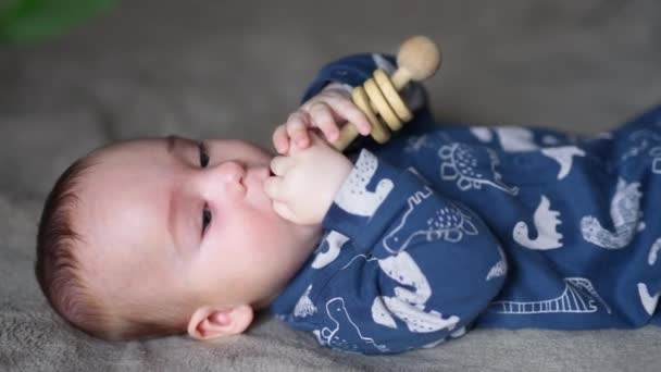Little Boy Blue Clothes Lies Back Holding Wooden Toy Hands — Stock Video