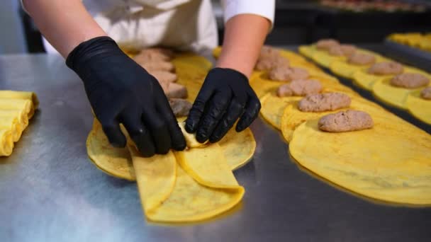 食品工場の労働者の手は 揚げられたミネラルミートを黄色いクレープに転がします 半分の食材を手作りしたもの クローズアップ — ストック動画