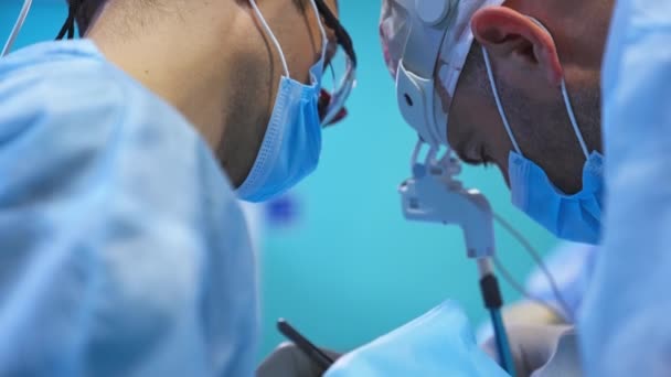 デバイスメガネ キャップ マスクの外科医の頭部は 操作を見下ろしています 保健医療の専門家の近くにポートレイト ブラーレッド バックドロップ — ストック動画
