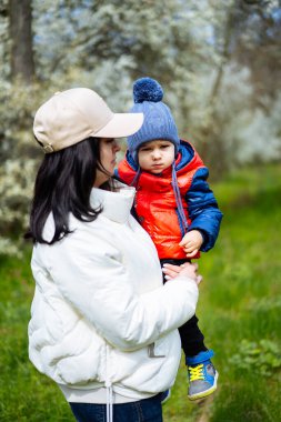 Genç anne küçük oğluyla parkta yürüyor..