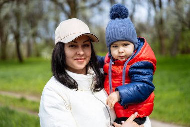 Genç anne küçük oğluyla parkta yürüyor. Konsept 