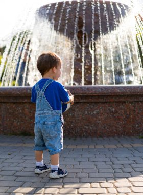 Küçük çocuk parkta fıskiyeyle oynuyor..
