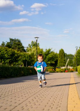 Küçük çocuk parkta yol boyunca koşar.