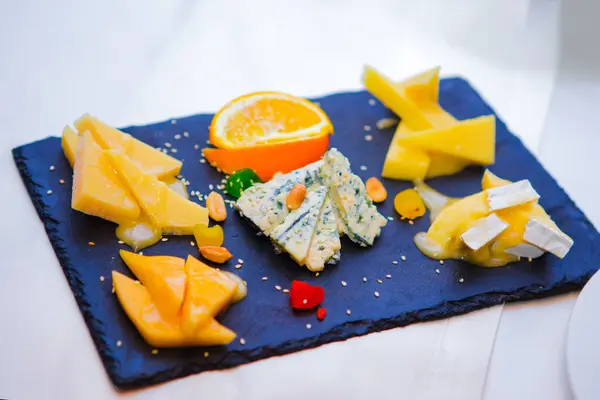 Cheese plate: Cheese plate with fruits and nuts on white table
