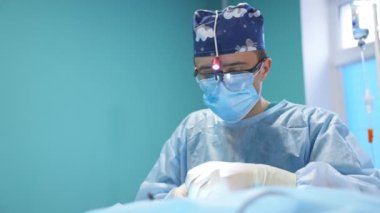 Genç erkek doktor ameliyata son veriyor. Modern kliniklerde işini yapan bir cerrahın yakın portresi..