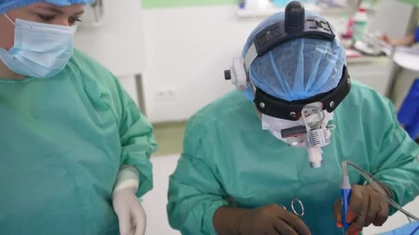 医疗小组在一个大手术室里进行耳鼻喉手术 主治医生坐在麻醉病人身边 — 图库视频影像