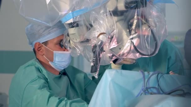 의사는 플라스틱으로 현미경으로주의 깊게보고 장비의 도움으로 신경외과 — 비디오