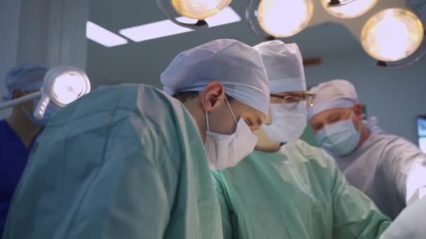 Equipe Masculina Cirurgiões Sob Lâmpadas Sala Cirurgia Especialistas Conduzindo Operação — Vídeo de Stock