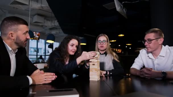 Four People Sit Table Jenga Block Pile Dark Haired Girl — Stock Video