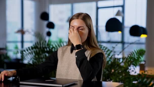 疲れた長髪の若い女性は コンピュータの仕事を終えました 女性は肘に彼女の頭を置き いくつかの休息を持っているために目を閉じます — ストック動画