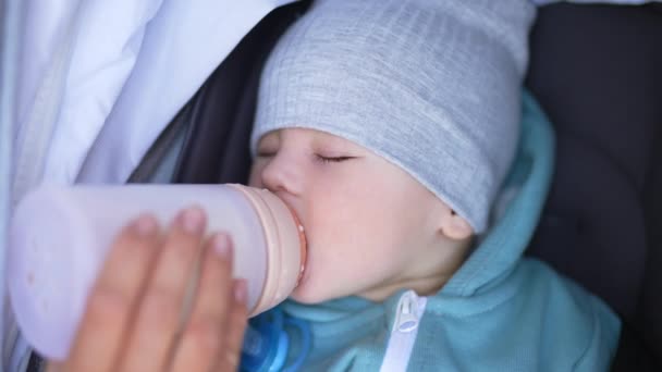 ボトルから牛乳を飲む灰色の帽子とブレーザーを身に着けている美しい子供 健康な赤ん坊の少年は目を閉じて眠りにつきました クローズアップ — ストック動画