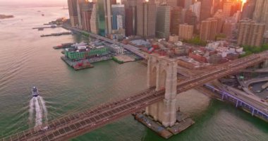 Batan güneş ışınlarında Manhattan Adası. Muhteşem Brooklyn Köprüsü ve rıhtımlarında uçan insansız hava aracı..