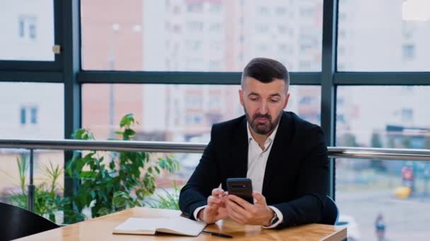 Poważny Facet Brodzie Siedzi Przed Oknem Garniturze Biznesmen Trzyma Telefon — Wideo stockowe