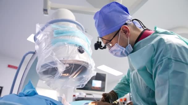 外科医はハサミを使用して患者の上に立っています ドクターは操作された患者を縫う操作を終えます — ストック動画