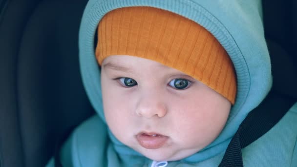 暖かい服を着て歩いている赤ちゃん 穏やかにカメラを見つめているキャップの美しい平和な子供 ポートレートを閉じる — ストック動画