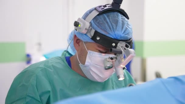 Cirujano Con Gafas Dispositivo Cabeza Sienta Cerca Del Paciente Hablando — Vídeo de stock