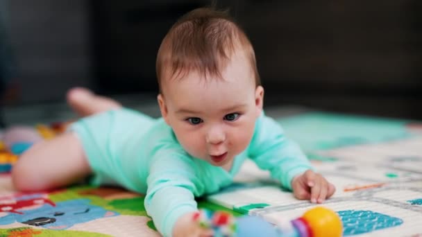 Милейший Ребенок Синем Костюме Пытается Дотянуться Своей Игрушки Забавный Малыш — стоковое видео