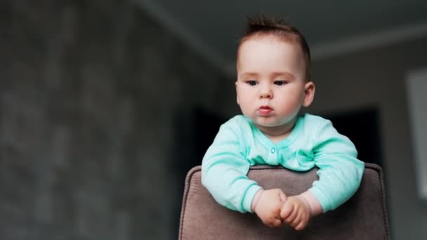Schatz Baby Steht Auf Stuhllehne Gestützt Nettes Kind Starrt Vor — Stockvideo