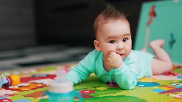 Любопытный Малыш Голубой Рубашке Лежит Коврике Животе Очаровательный Ребенок Жует — стоковое видео