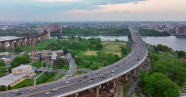 New York nehrini geçen iki köprü. Köprülerden birine giden yoğun bir otoyol. Arkaplanda yeşil parklar ve şehir.