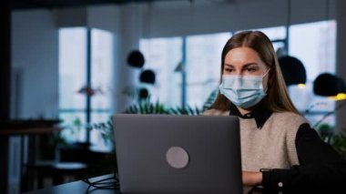 Ofiste salgın bir çalışma dönemi. Maskeli kadın oturur ve dizüstü bilgisayarıyla çalışır. Kadın işçi onları takmak için gözlük takıyor..