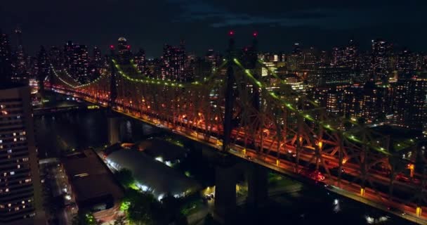 夜間に美しく強調されたクイーンズボロ橋 ドローンが活気に満ちた街を飛び回っている ニューヨークの数十億光 — ストック動画