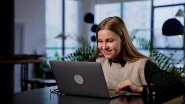 彼女のコンピュータで働く若い女性を微笑ませる 幸せな女性はいくつかの結果に満足し 成功ジェスチャーを作ります ブラーレッド バックドロップ — ストック動画