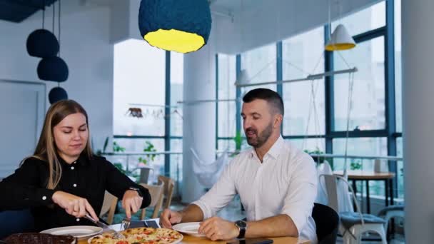 オフィスで昼食をとっている同僚 ワーキングチームは大きなテーブルにピザを座らせたい — ストック動画