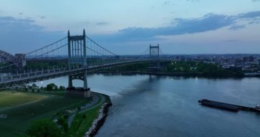 East River 'da yüzen feribot. Güzel Triborough Köprüsü 'nün altından geçen bir nakliye aracı. New York 'ta akşam vakti.