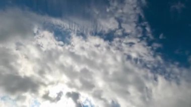 Beyaz pamuk bulutları hızla gökyüzünde uçuyor. Mavi ve güneşli gökyüzünün arka planında ağır bulutlar. Aşağıdan görüntüle.