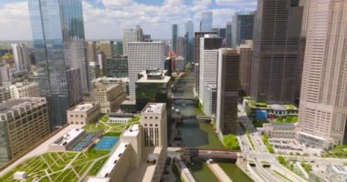 Harika Chicago 'nun fantastik binaları. İnsansız hava aracı, binaların üzerinde yeşil alanlar, nehrin üzerinde birden fazla köprü ile uçuyor. Arkaplanda bulutlu gökyüzü.