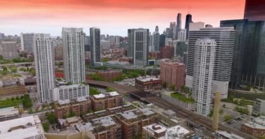 Güzel binaların arasından geçen metro rayları. Pembe gökyüzünün arka planında muhteşem Chicago şehri.