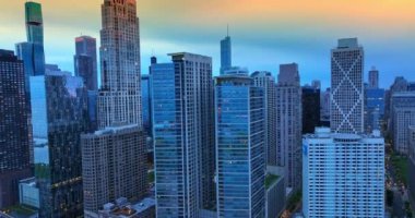 Chicago gökdelenleri akşam vakti maviye boyanmış. Güneşin batışında güzel gökyüzünün arka planındaki çarpıcı gökdelenler boyunca insansız hava aracı görüntüleri yükseliyor..