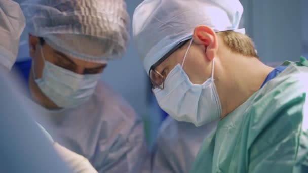 手術中の医師の協力チーム キャップとマスクの男性外科医は手術室で働いています — ストック動画