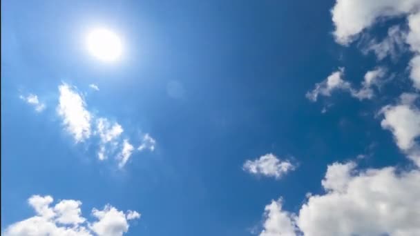 青空に輝く明るい太陽 すぐに太陽に向かって白い雲を飛ぶ 下からの眺めです タイムラプス — ストック動画