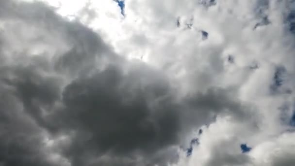 青い空を完全に覆っている灰色の雲 明るい太陽が雲を通り抜けている タイムラプス — ストック動画
