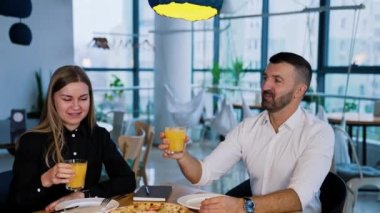 Mutlu gülümseyen gençler masada meyve suyuyla bardaklarını tokuştururlar. Arkadaşlarla birlikte pizza yemeye gelmiştik..