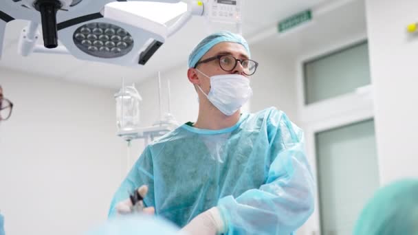 手術中にモニターを観察する非常に集中した外科医 職場の専門家の肖像画 ローアングルビュー — ストック動画