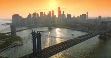 Gün batımında Manhattan Köprüsü 'nde çılgın bir trafik var. Göz kamaştırıcı New York gökdelenleri Pembe gökyüzü ve parlak batan güneşin arka planında.
