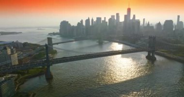Çarpıcı New York 'u birbirine bağlayan köprüler. İHA, batan güneşi yansıtan Doğu Nehri üzerinde uçuyor. Pembe gökyüzü arkaplanı.