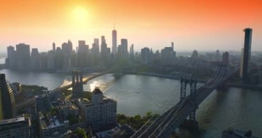 Batan güneşin son ışınlarında New York. Brooklyn ve Manhattan köprüleri doğu nehri üzerinde. Tekne de yol alıyor. Hava görünümü.