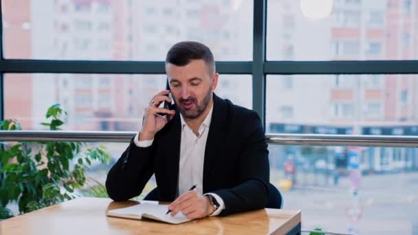 Zajęty Człowiek Rozmawiający Przez Telefon Notujący Swoim Notatniku Pewny Siebie — Wideo stockowe