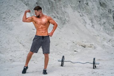 Kaslı adam sahilde pazılarını çalıştırıyor..