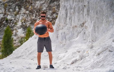 Genç atletik adam beyaz dağda topla antrenman yapıyor.