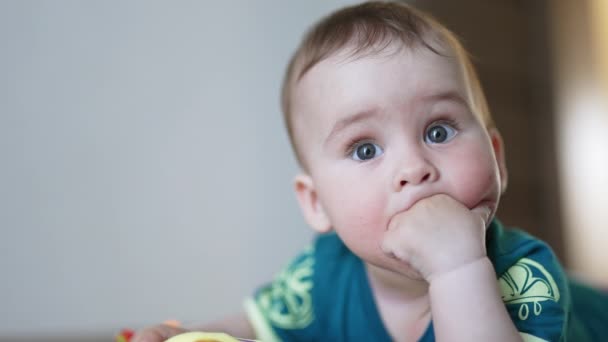 有思想的婴儿把拳头放在嘴里 平静可爱的小孩看着玩具 靠近点模糊的背景 — 图库视频影像