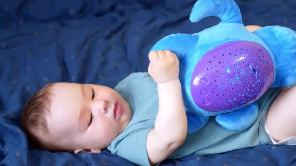 Υπέροχο Μωρό Ξαπλωμένο Στο Κρεβάτι Παίζει Ένα Μαλακό Παιχνίδι Αξιολάτρευτο — Αρχείο Βίντεο