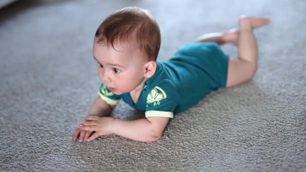 小さな子供は喜んで床の上に手を叩きました 美しい子供は興味を持って見上げるカーペットの上に横たわる — ストック動画