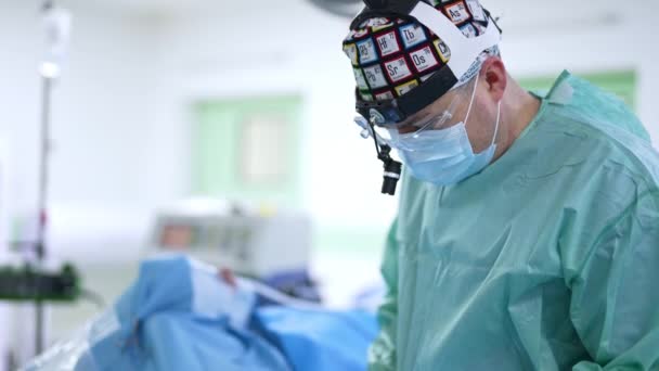 外科医のオトリガー科医が手術を行っています 頭にマスクとデバイスを着用する医師は 患者の鼻を操作するツールを使用します — ストック動画