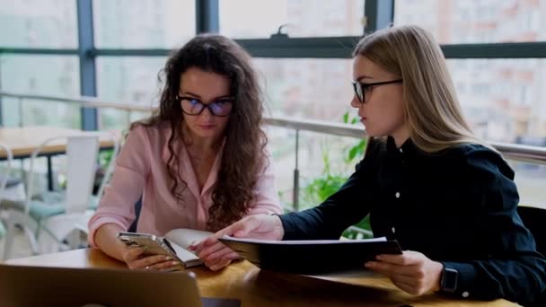中年女商人讨论工作问题 戴眼镜 头戴长发的女人坐在办公桌前 看着电话 与人交流 — 图库视频影像