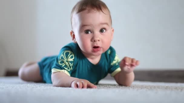 바닥에 귀여운 아기는 카펫에 관심과 호기심으로 주변을 봅니다 — 비디오